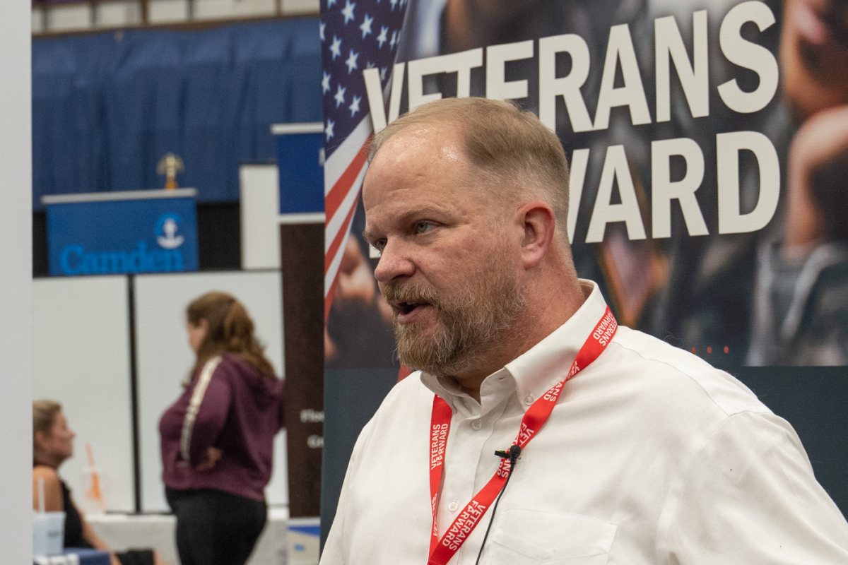 Man in front of Veterans Forward banner